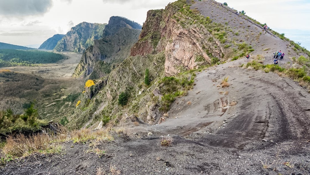 Hikers on a trail at Vesuvius National Park with volcanic landscape.