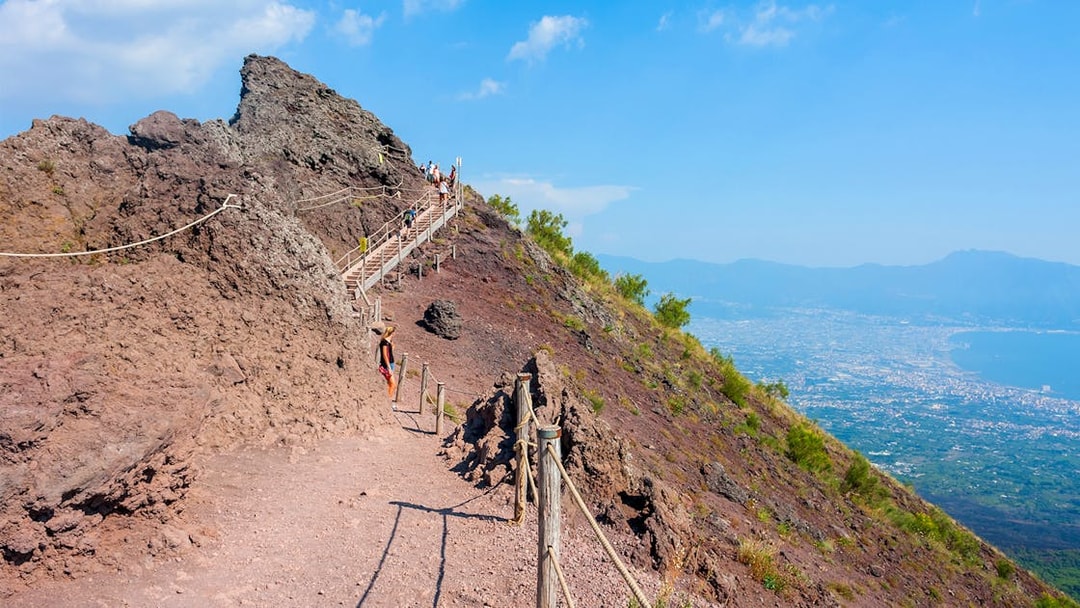 Hikers ascending Mount Vesuvius with panoramic views of Naples and the coastline.