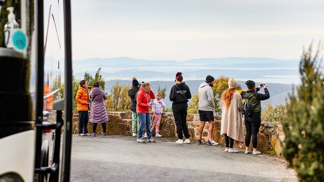 Tour group enjoying scenic view from Mt Wellington lookout, Tasmania.