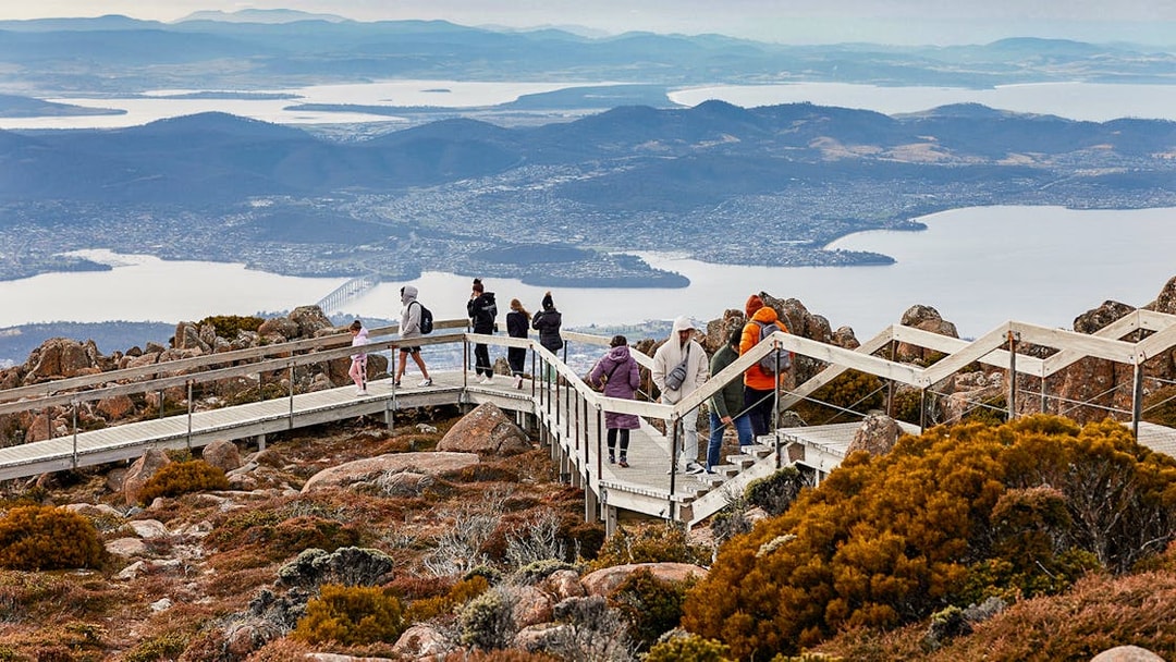 Visitors walking on Mt Wellington boardwalk with views of Hobart, Tasmania in the background.
