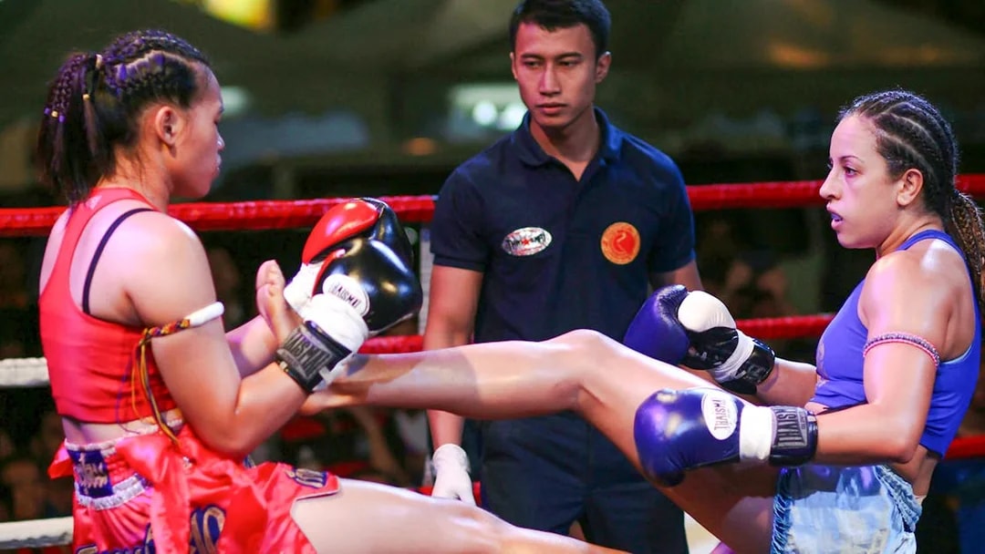 Two fighters in a Muay Thai match at Bangla Boxing Stadium, referee observing.