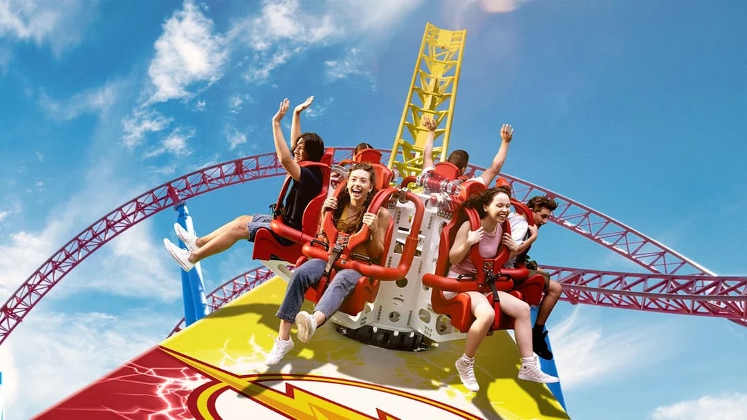 Tourists enjoying the Flash ride at Movie World with vibrant roller coaster tracks.
