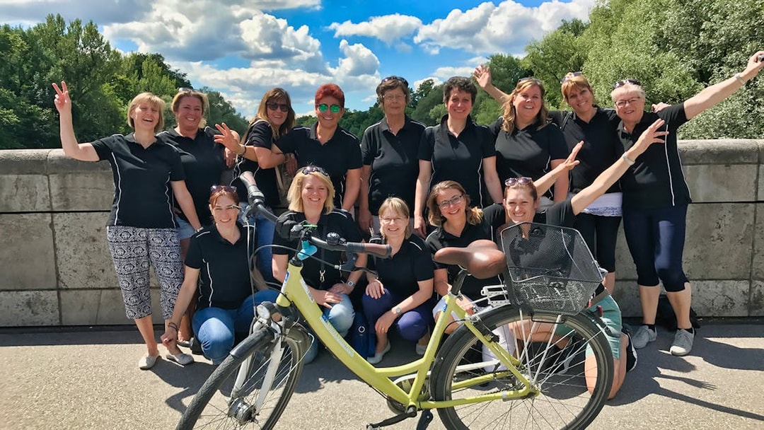 Group of people posing with a bike on a bridge during a Munich bike tour.