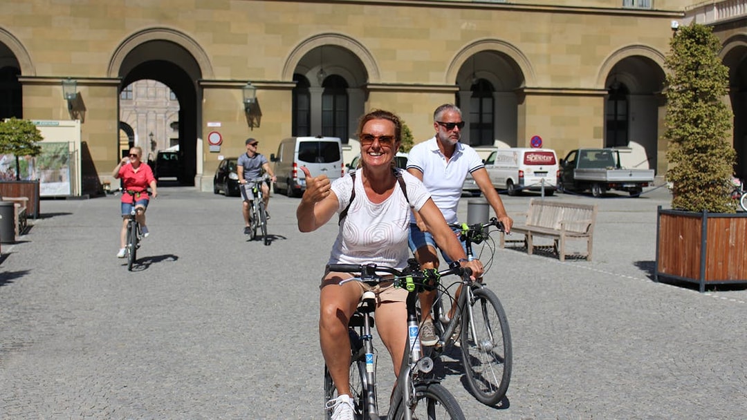 Cyclists enjoying a sunny day on a Munich bike tour near historic architecture.