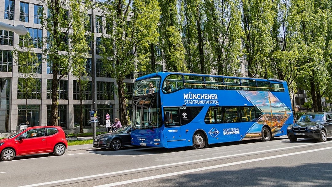 Blue double-decker bus on Munich street for Hop-On/Hop-Off Express Tour.
