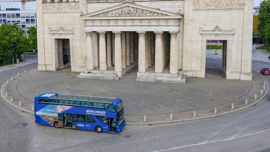 Open-top tour bus in front of Munich's Propylaea on a Hop-On/Hop-Off Express Tour.