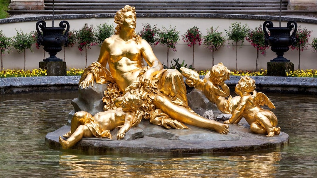 Golden statue in Linderhof Palace garden fountain, part of a day trip from Munich to Neuschwanstein.