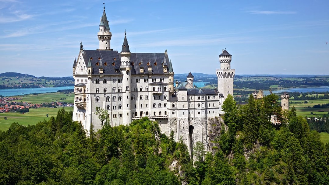 Neuschwanstein Castle surrounded by lush greenery, viewed on a day trip from Munich.