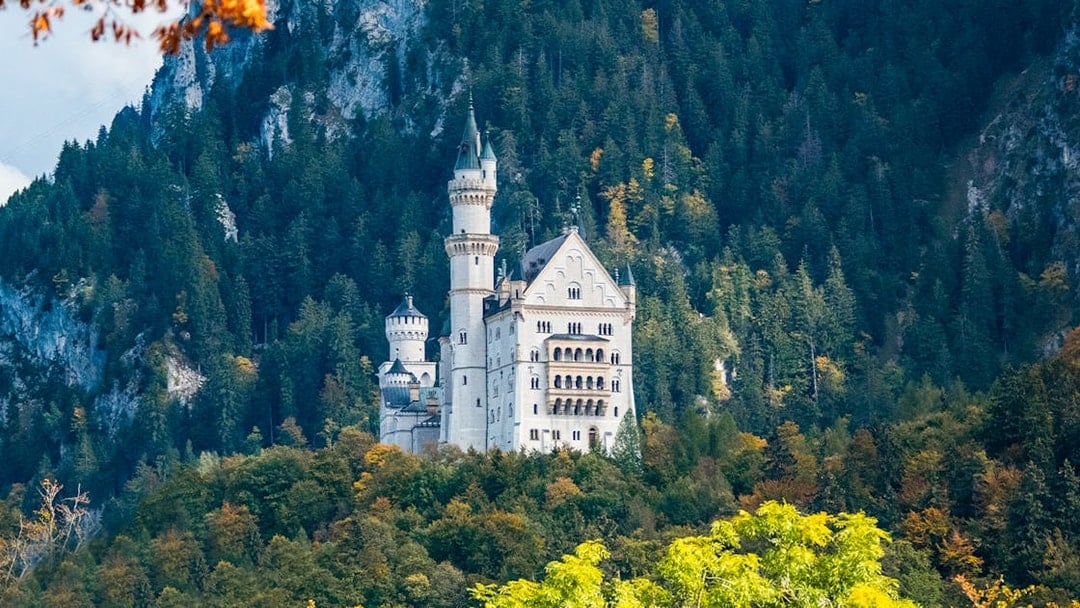 Neuschwanstein Castle surrounded by forested hills, part of the Skip The Line tour from Munich.
