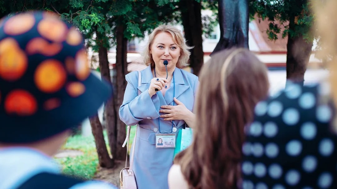 Tour guide speaking to a group outdoors with trees in the background.