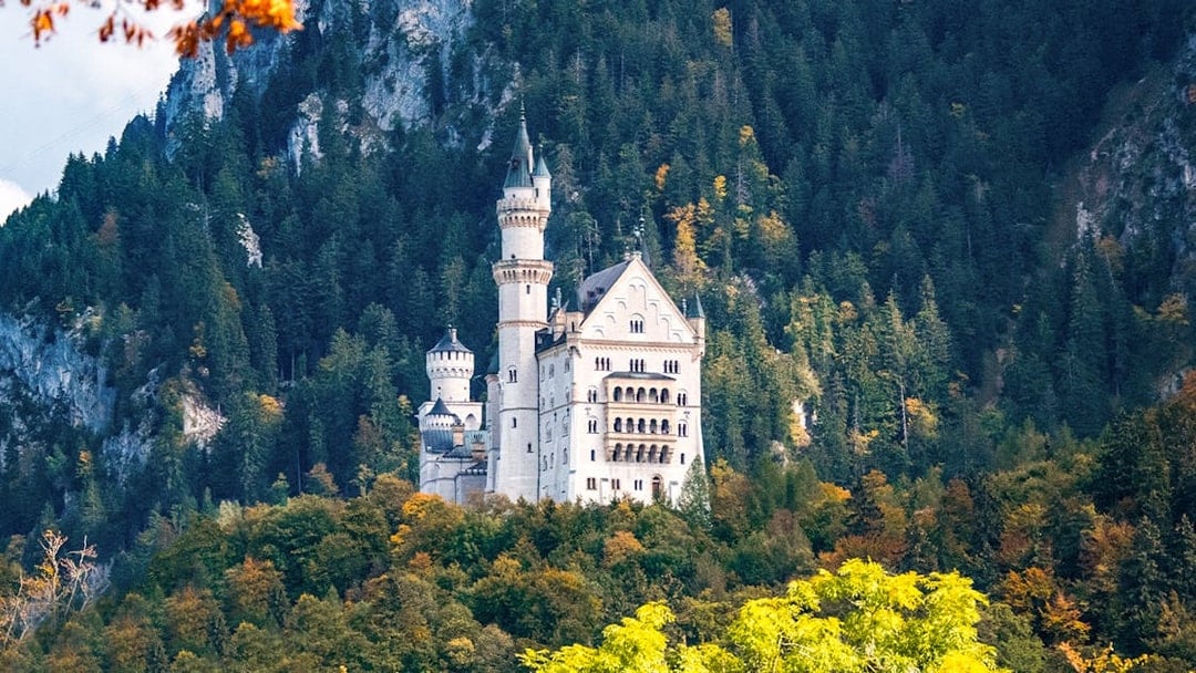 Neuschwanstein Castle surrounded by forested hills in Bavaria, Germany.