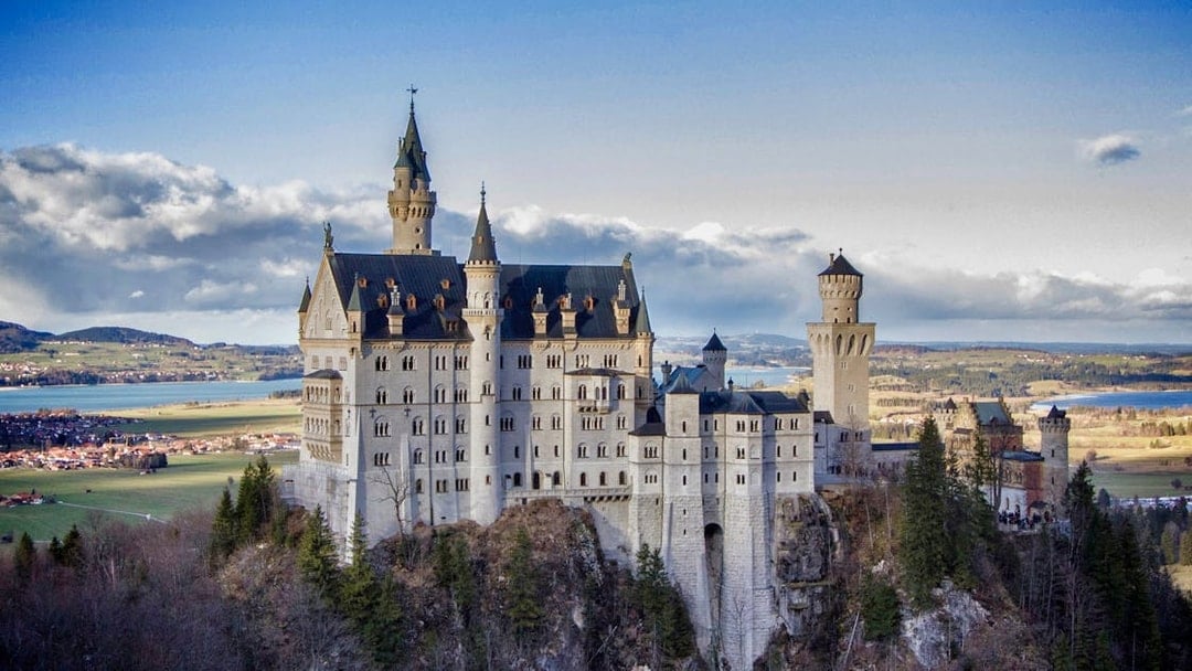 Neuschwanstein Castle in Bavaria, Germany, viewed from a distance with surrounding landscape.