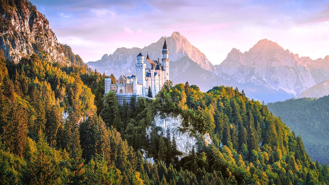 Neuschwanstein Castle surrounded by forested mountains in Bavaria, Germany.