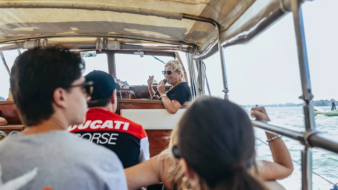 Boat tour guide giving live commentary to passengers on Murano and Burano Islands tour.