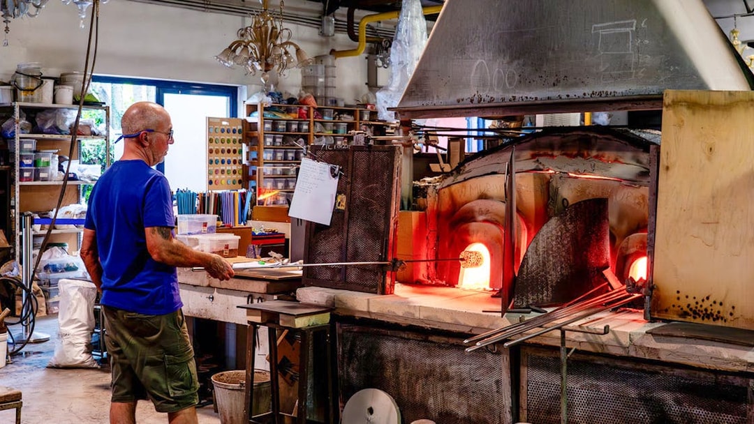Glassblower working at furnace in Murano workshop.