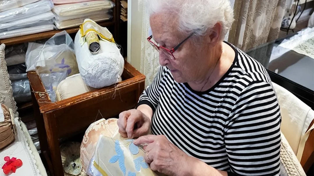 Elderly woman crafting lace at Burano lace school.
