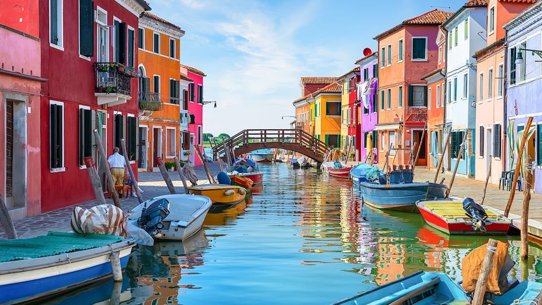 Colorful houses and boats along the canal near Tre Ponti Bridge, Burano island, Venice.