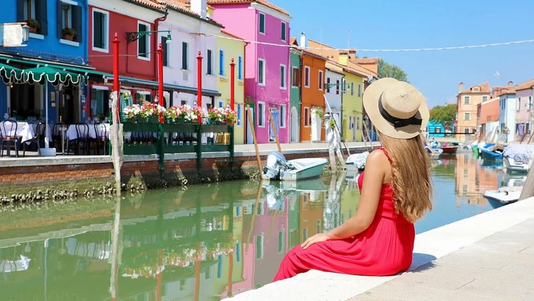 Girl admiring colorful buildings along a canal in Murano, Italy.