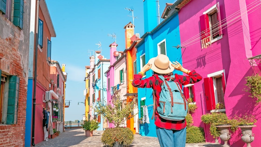 Colorful houses on Burano Island with a tourist exploring the vibrant street.