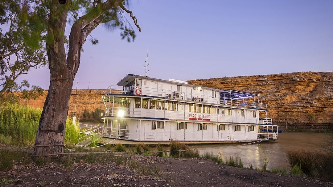 Paddle steamer on Murray River at sunset with cliffs in the background.
