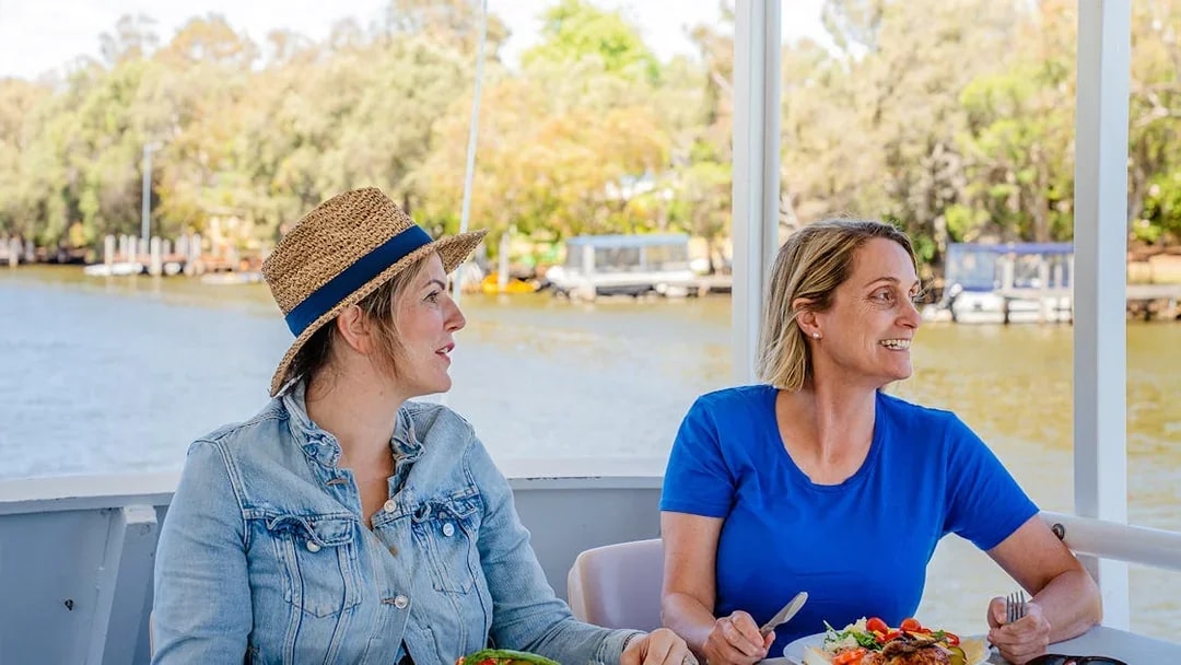 Two people enjoying lunch on a Murray River cruise with scenic river views.