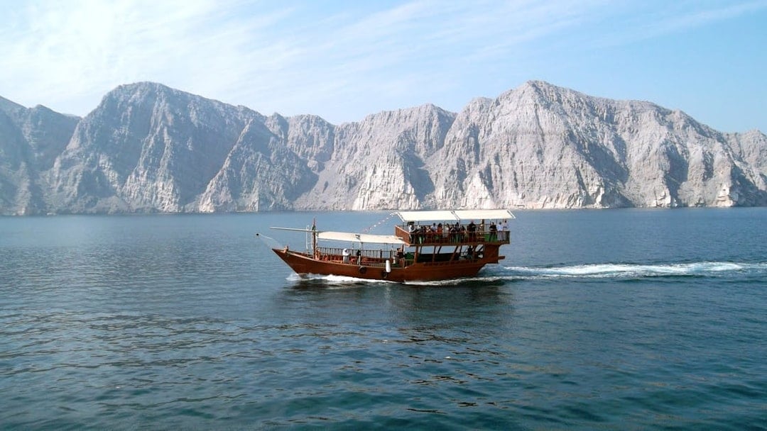 Dhow cruise on Musandam Dibba waters with rocky mountains in the background.