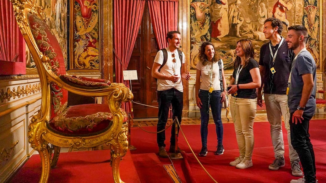 Tour group admiring ornate throne room in the Royal Palace of Madrid, Spain.