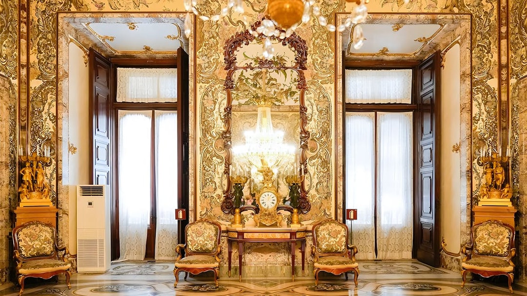 Interior of Royal Palace of Madrid with ornate decor, chandeliers, and antique furniture.