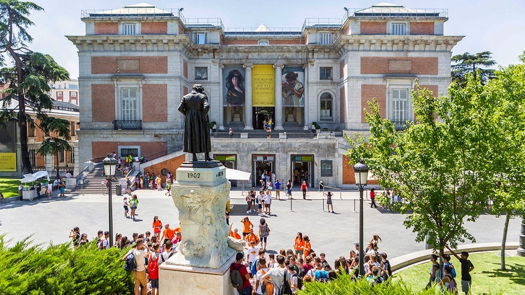 Prado Museum entrance with visitors and statue in Madrid, Spain.