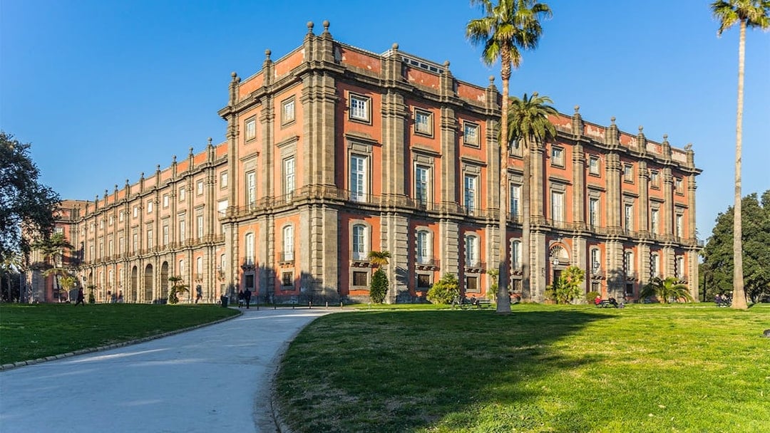 Capodimonte Museum exterior with palm trees and pathway in Naples, Italy.