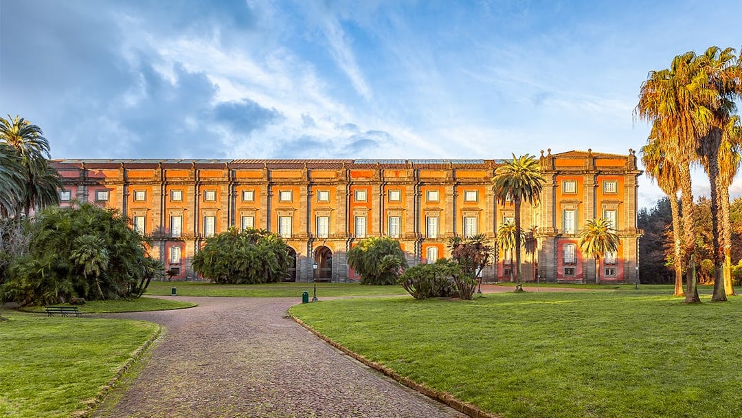 Courtyard of Capodimonte Museum with palm trees and historic building in Naples, Italy.