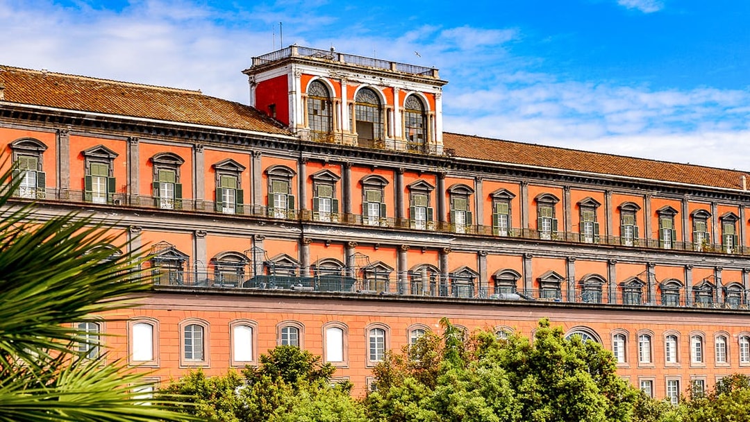 Capodimonte Museum exterior with red facade and arched windows in Naples, Italy.