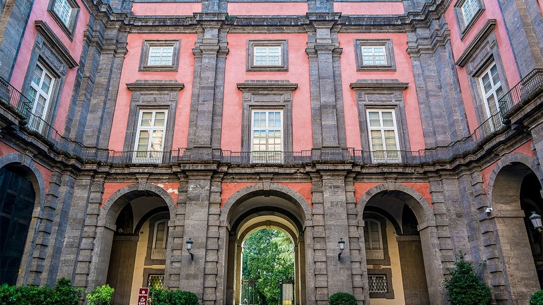Capodimonte Museum exterior with arched entrance and pink facade in Naples, Italy.