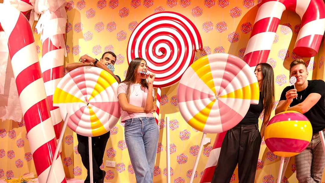 Guests posing with giant candy props at Museum of Candy.
