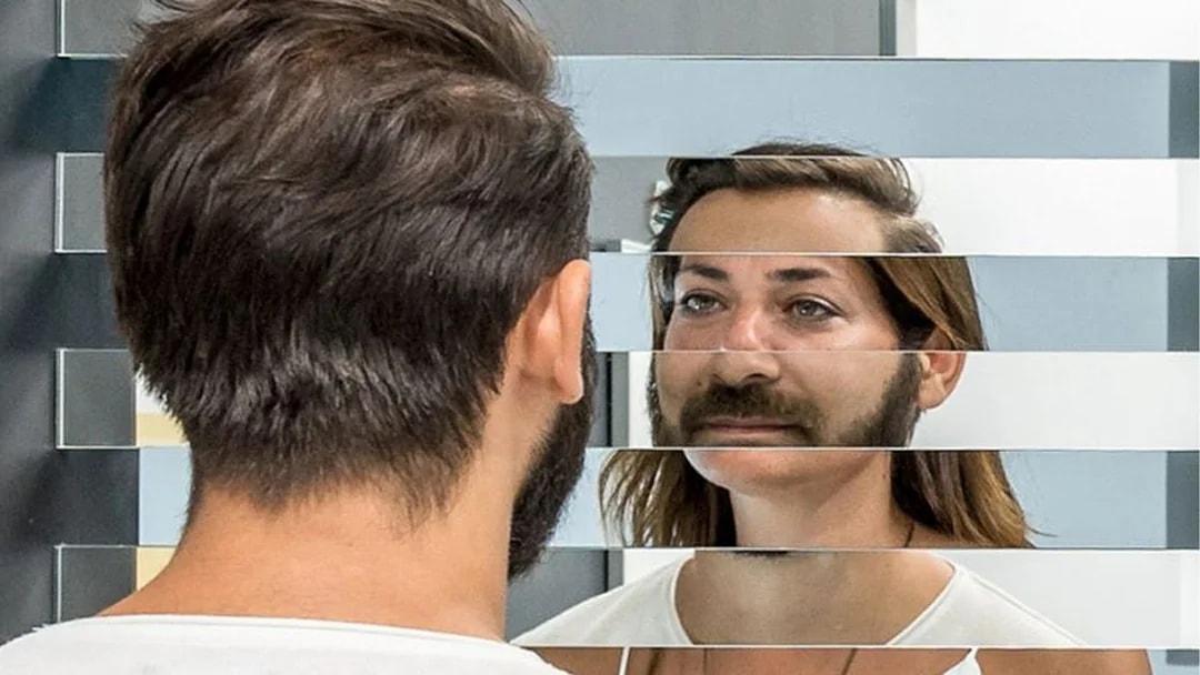 Person viewing fragmented reflection in mirror exhibit at Museum of Illusions.