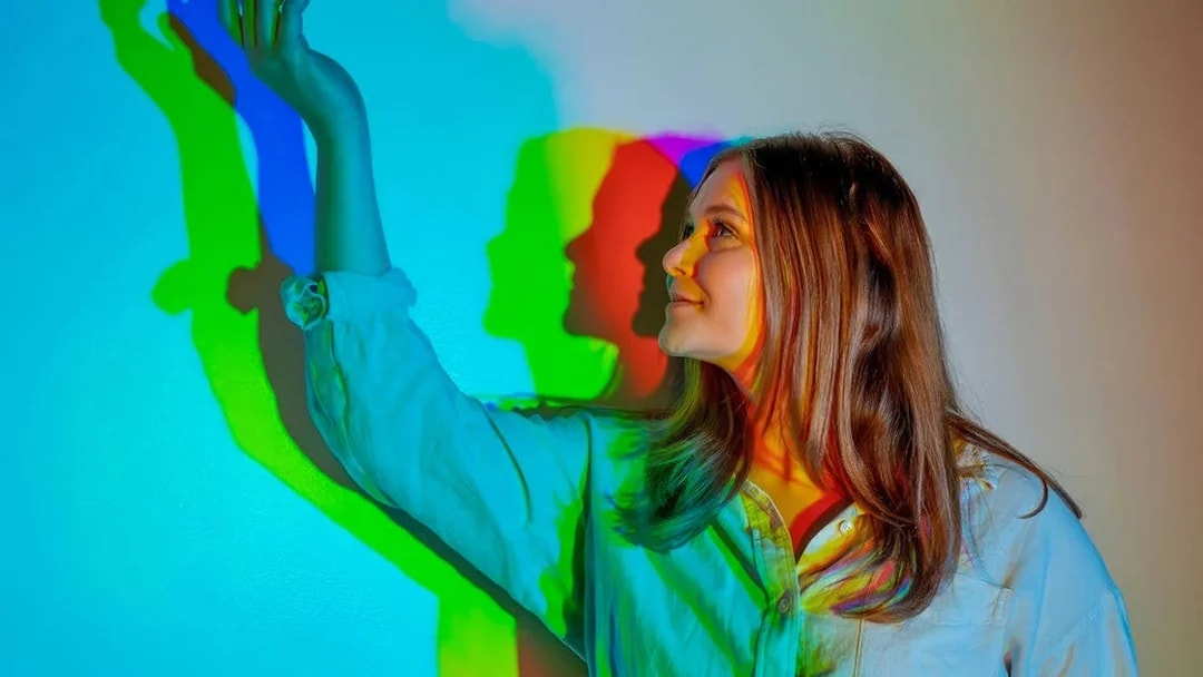 Person interacting with colorful light shadows at Museum of Illusions Dubai.
