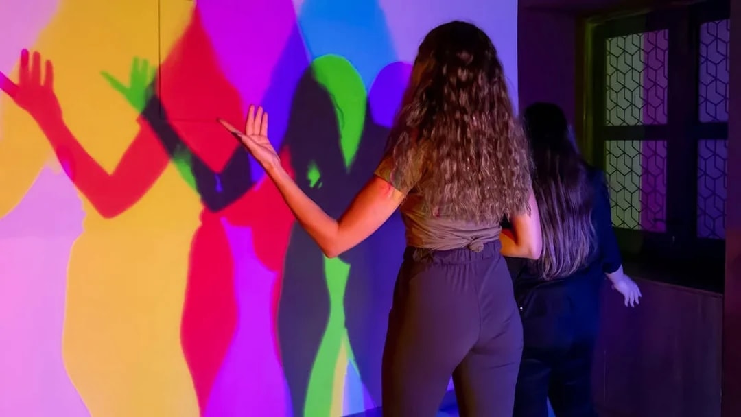Visitors interacting with colorful light shadows at Museum of Illusions Dubai.