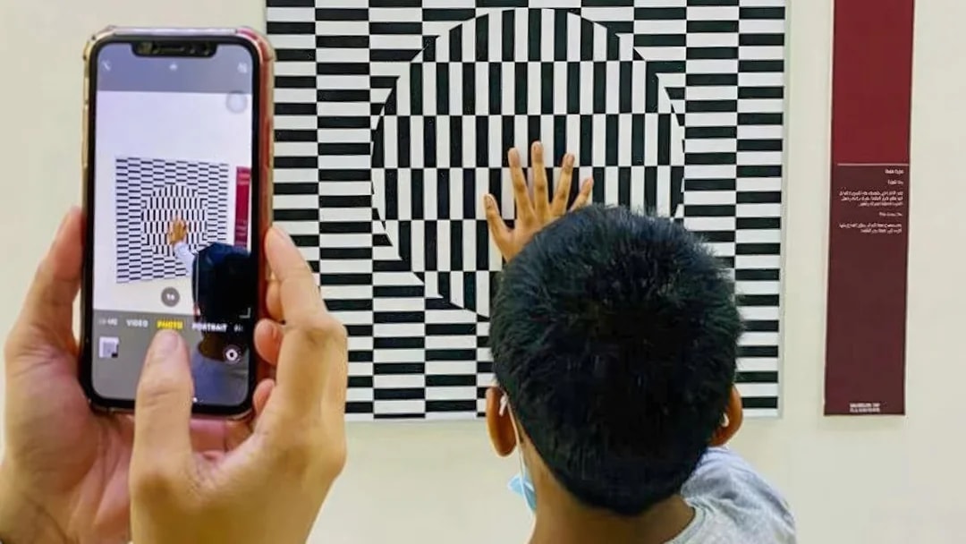 Child interacting with optical illusion exhibit at Museum of Illusions Dubai.