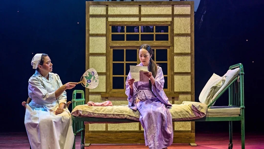 Stage scene from My Neighbour Totoro with two actors, one reading a letter.