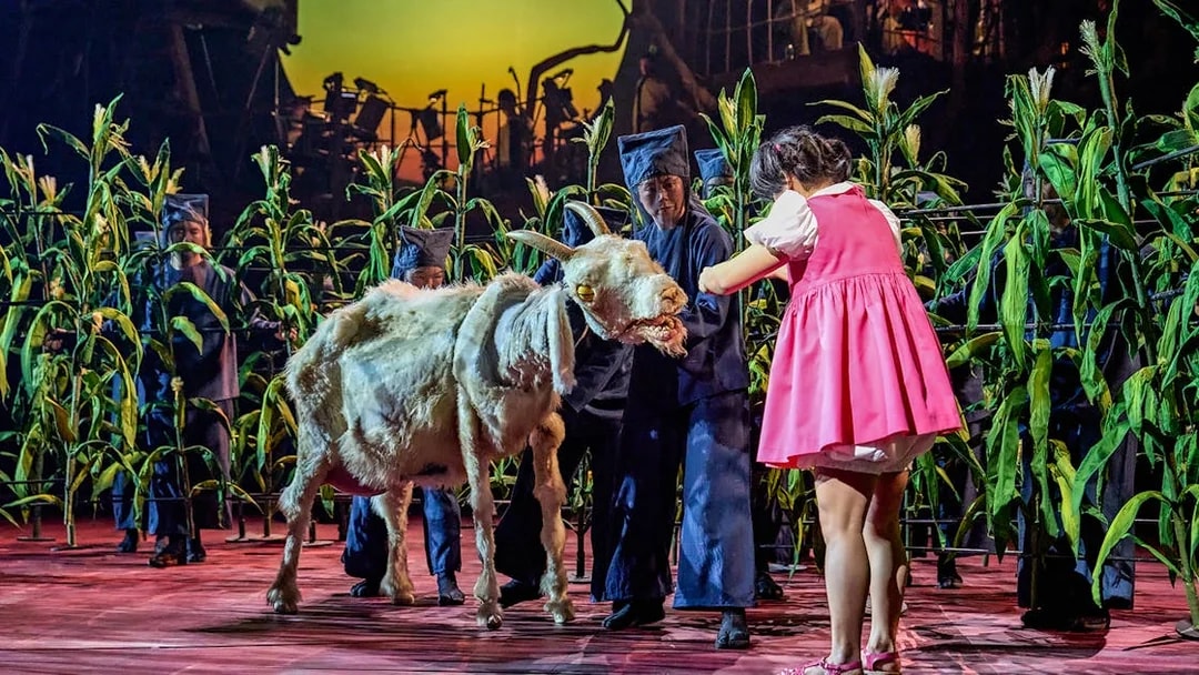 Stage performance of My Neighbour Totoro with actors and a goat puppet among corn stalks.