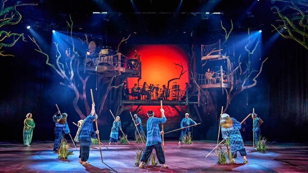 Stage performance of My Neighbour Totoro with actors holding sticks, vibrant backdrop.