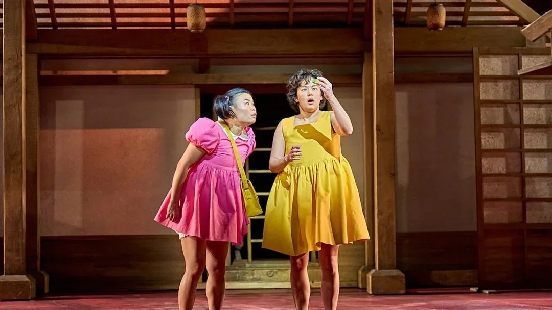 Two actors on stage in colorful dresses during a My Neighbour Totoro performance.