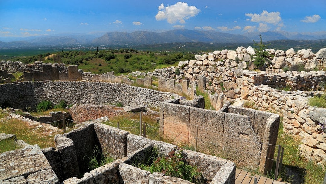 Mycenae archaeological site with ancient stone walls and distant mountain view.