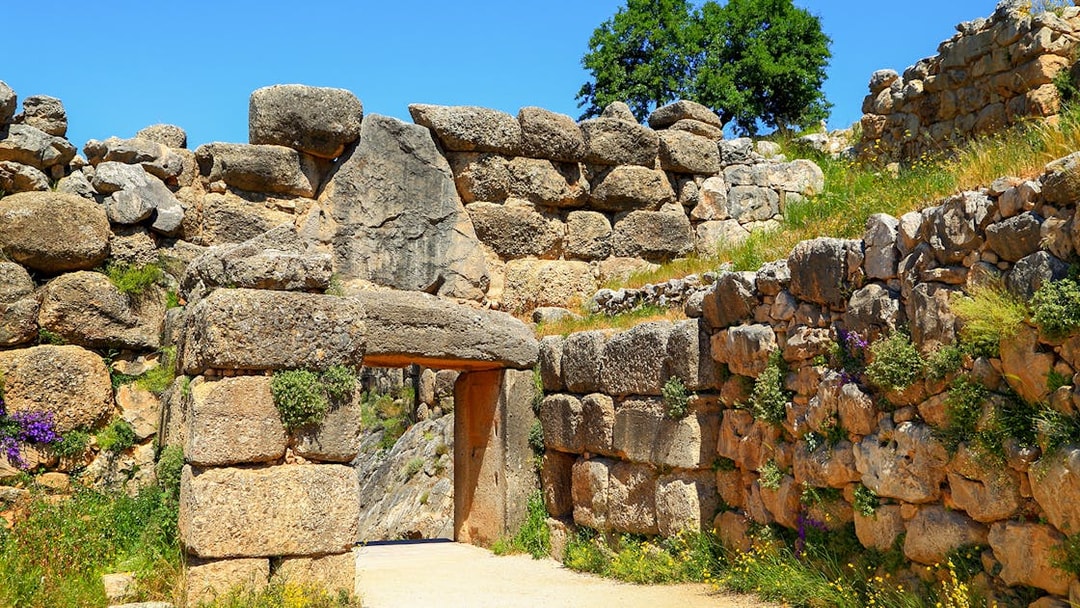 Mycenae archaeological site entrance with ancient stone walls and greenery.