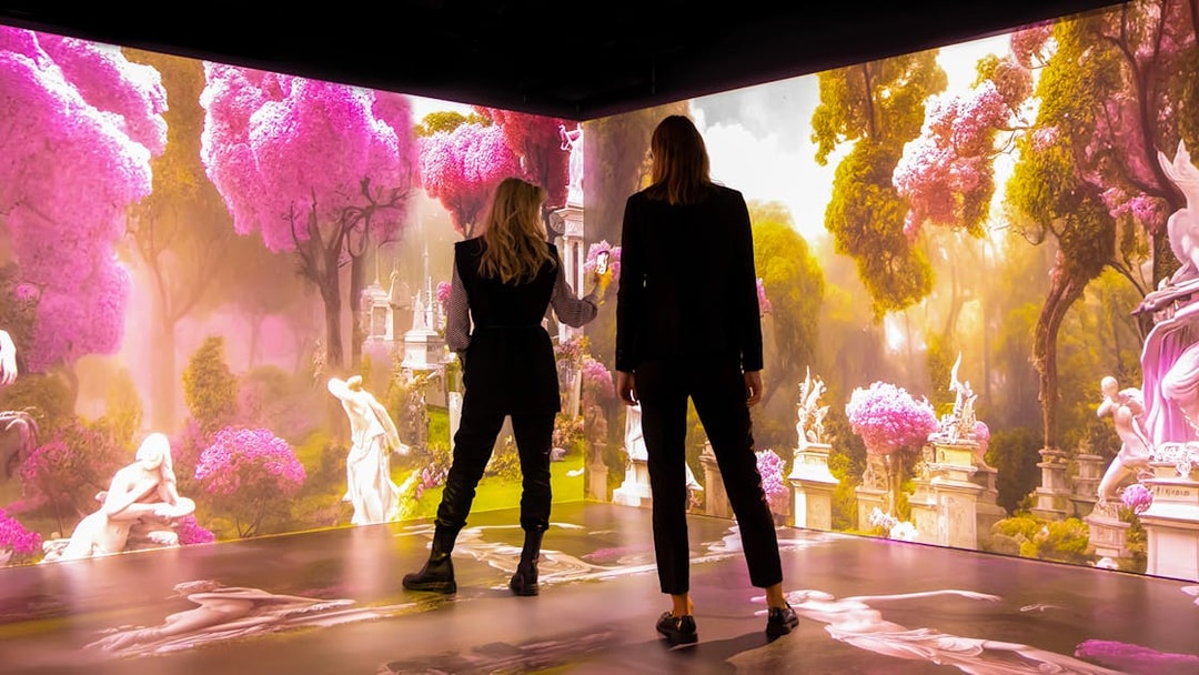 Visitors exploring immersive Mythos Mozart exhibit with vibrant pink trees and classical statues.