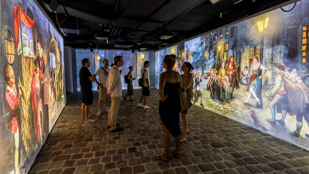 Visitors viewing immersive Mozart-themed projections at an exhibition.