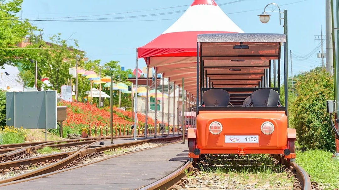 Orange Gangchon Rail Bike on tracks near station, South Korea.