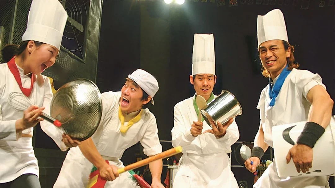 Performers in chef outfits playing kitchen instruments at Seoul Myeongdong Nanta Musical Show.