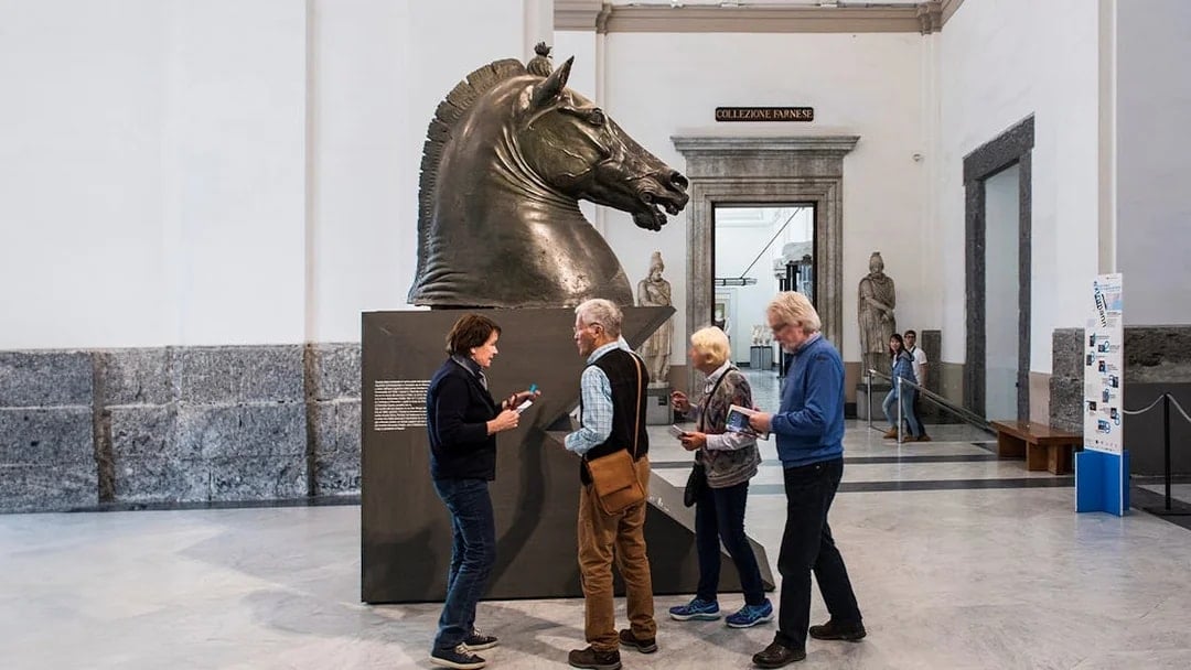 Visitors examining a horse sculpture at Naples National Archaeological Museum.