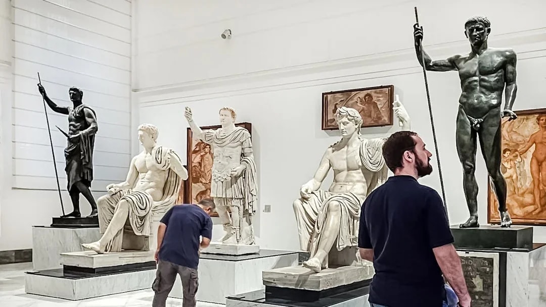 Visitors viewing classical statues at Naples National Archaeological Museum.